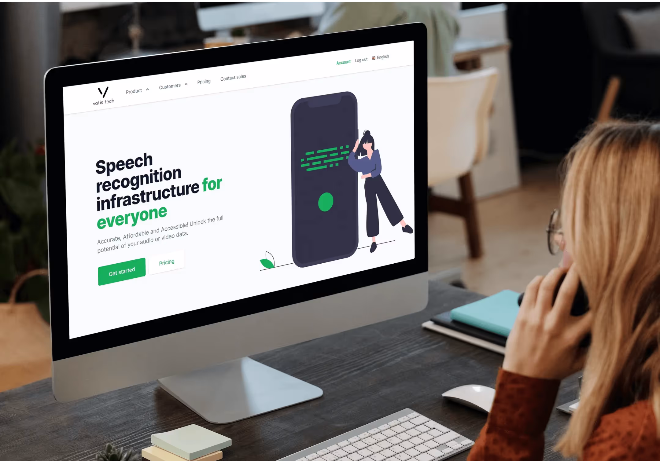 Woman at a desk viewing the Vatis Tech speech recognition homepage on a large monitor